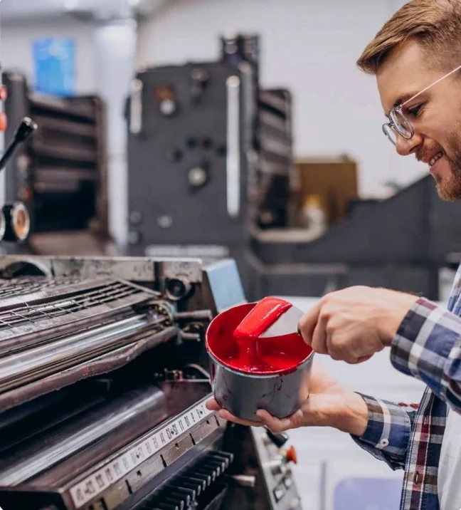 Printing technician preparing red ink on an industrial press